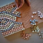 Motif de tresse en cours de confection avec des tesselles colorées de mosaïque